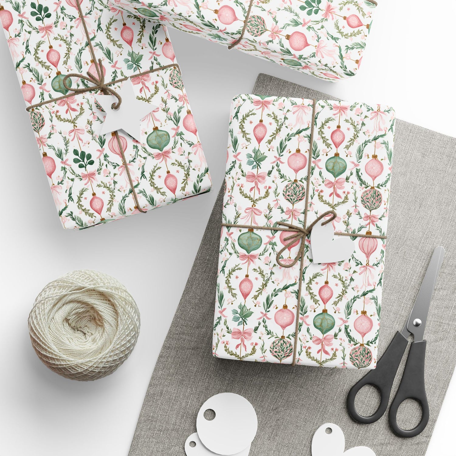 Gift boxes wrapped in festive paper with decorative ribbons, scissors, and yarn on a white surface.