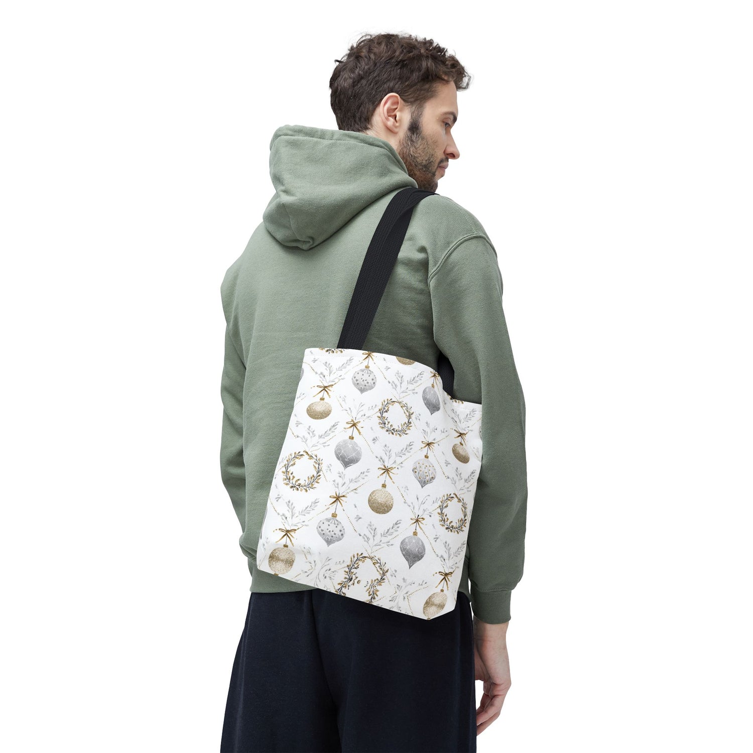 Man wearing a green hoodie with a white tote bag featuring Christmas ornaments and wreaths.
