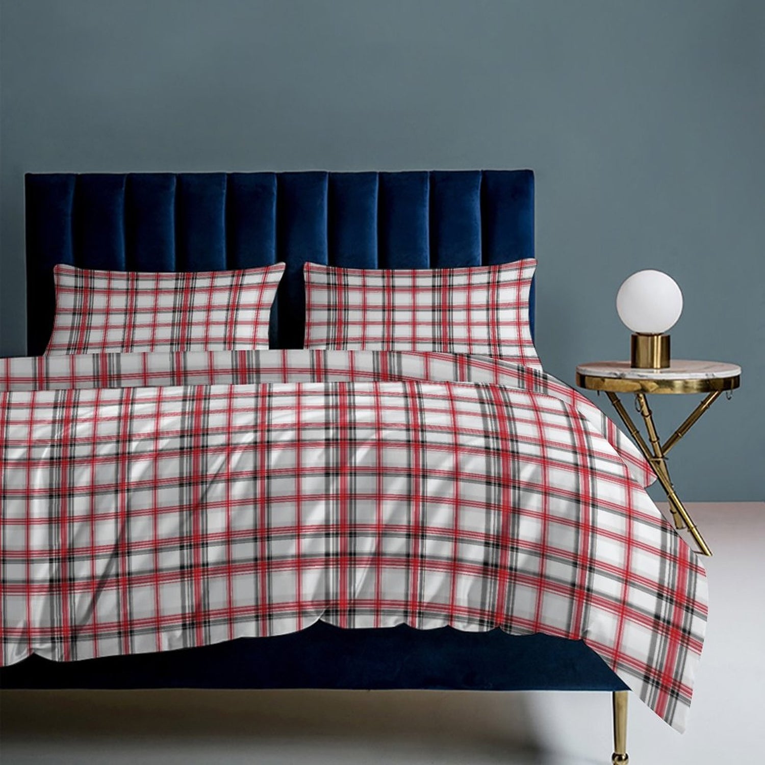 Plaid bedspread on a bed with a blue headboard and side table against a gray wall.