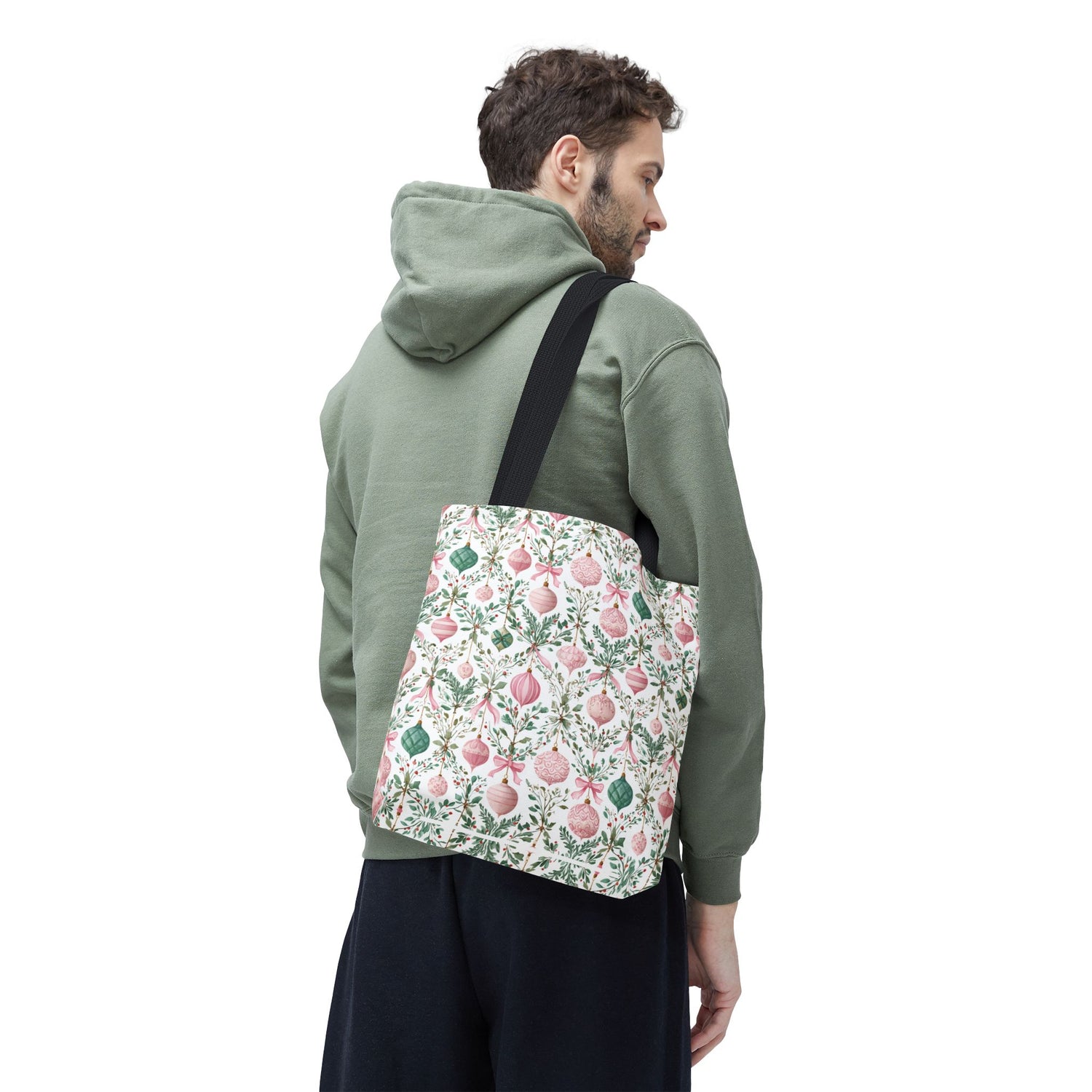 Person wearing a green hoodie with a floral-patterned bag over one shoulder on a white background