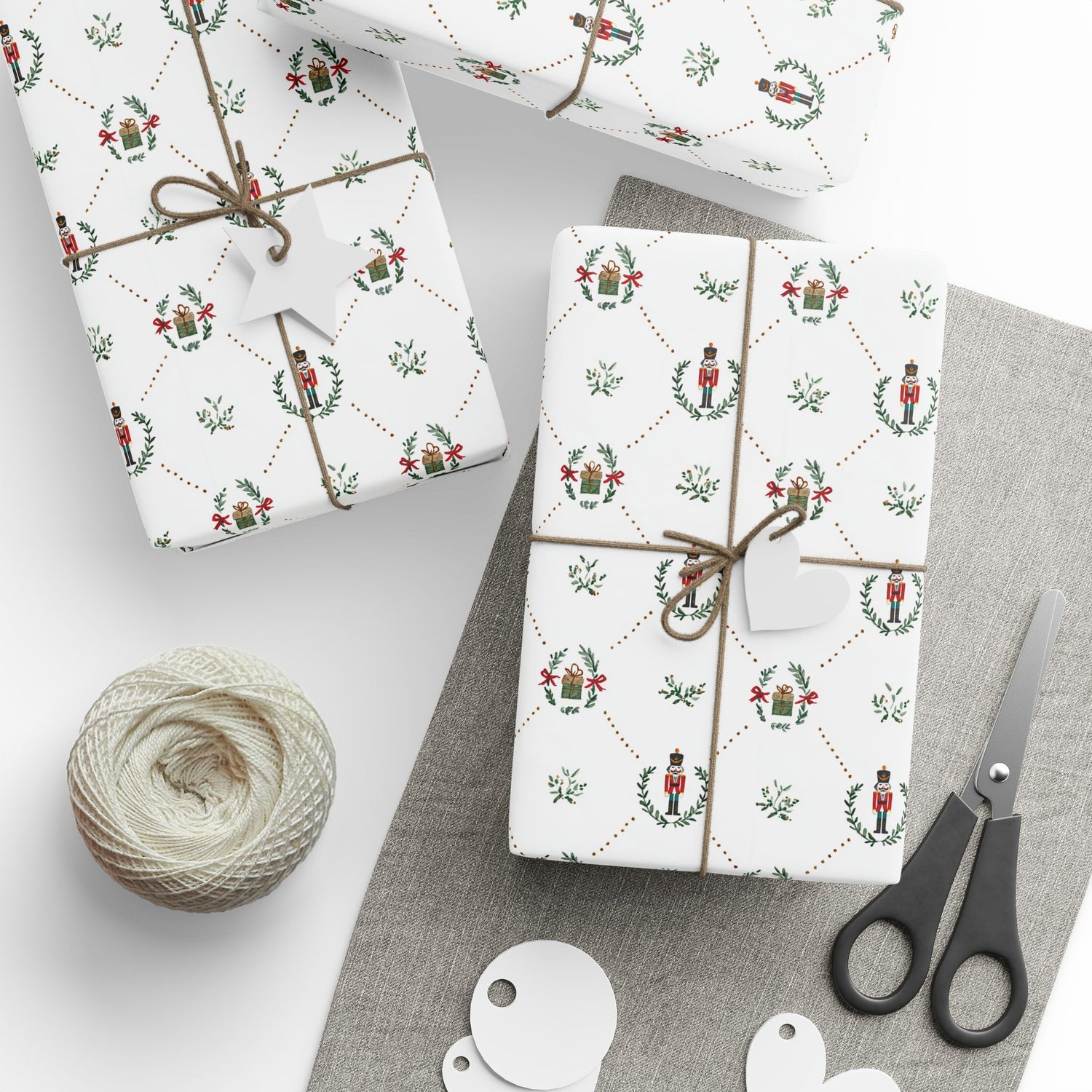 Gift boxes wrapped in festive paper with a ball of twine and scissors on a gray surface.
