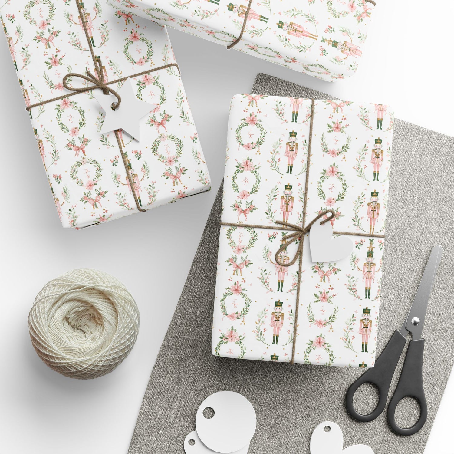 Gifts wrapped in decorative paper with a ball of string and scissors on a white surface